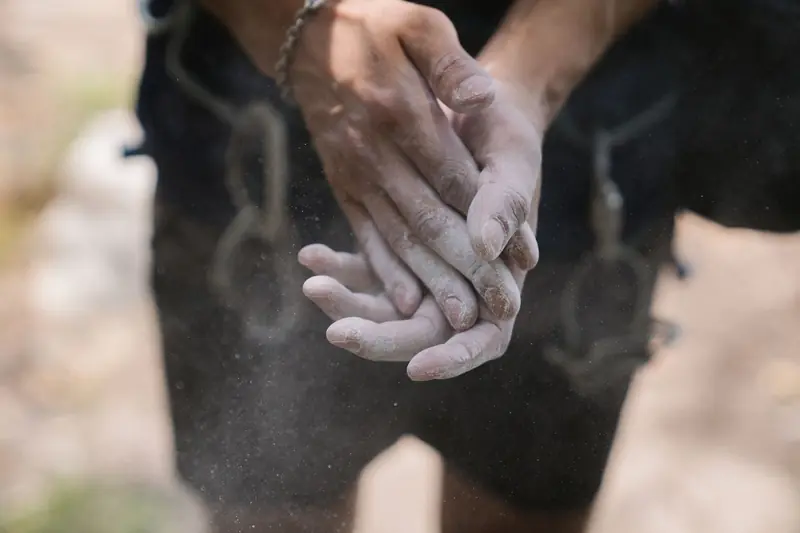 Hands covered in chalk dust, preparing for rock climbing. Blurred background enhances focus