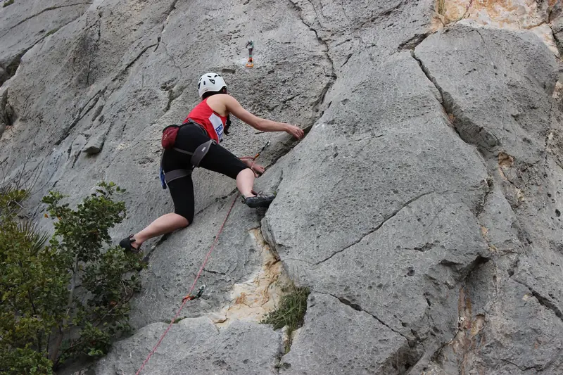 A climber ascends a rugged cliff face in El Chorro, Andalusia, Spain, capturing adventure and skill