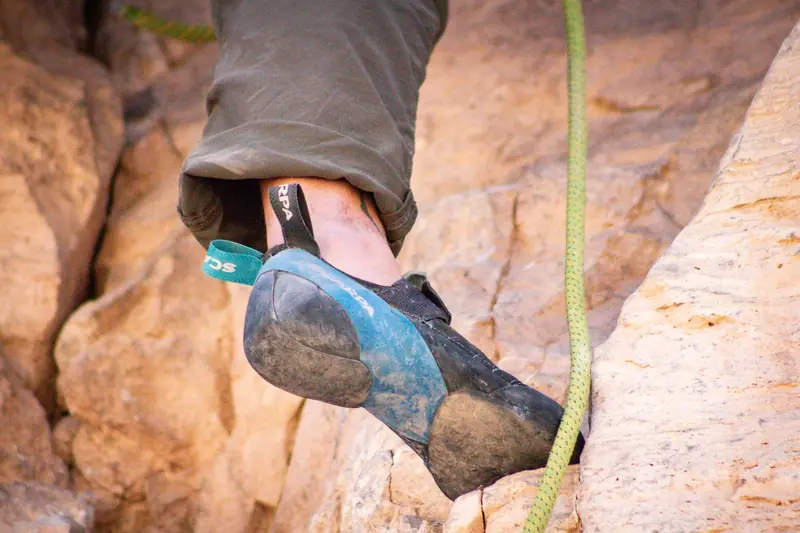 Close-up image of a climber's foot in a rock climbing shoe gripping a rocky surface