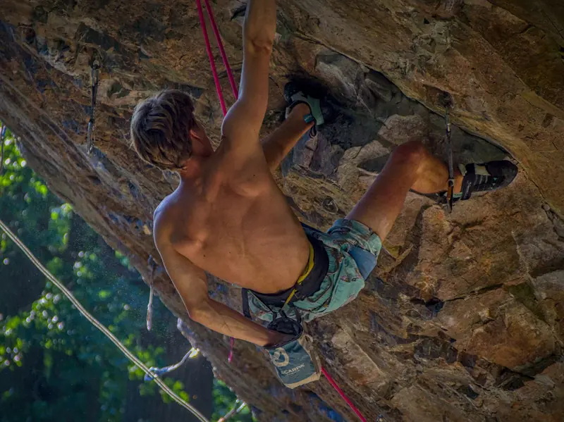Adventurous rock climber tackles a challenging overhanging cliff with determination. Perfect shot of sportsmanship