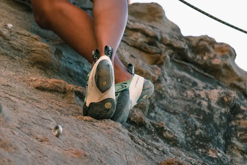 A close-up view of a climber's feet in climbing shoes clutching a rocky surface enhancing the thrill of climbing