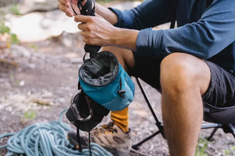 Close-up of a person packing climbing gear with rope and chalk bag outdoors