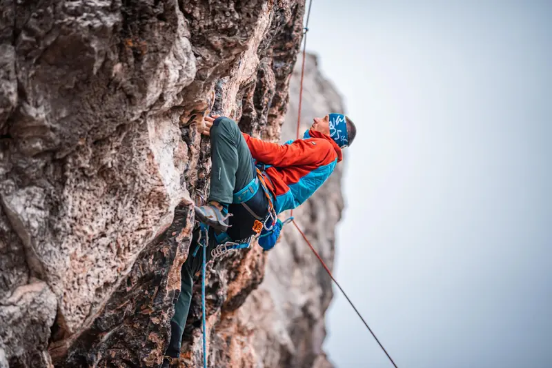 A daring rock climber ascends a steep cliff face with determination and skill