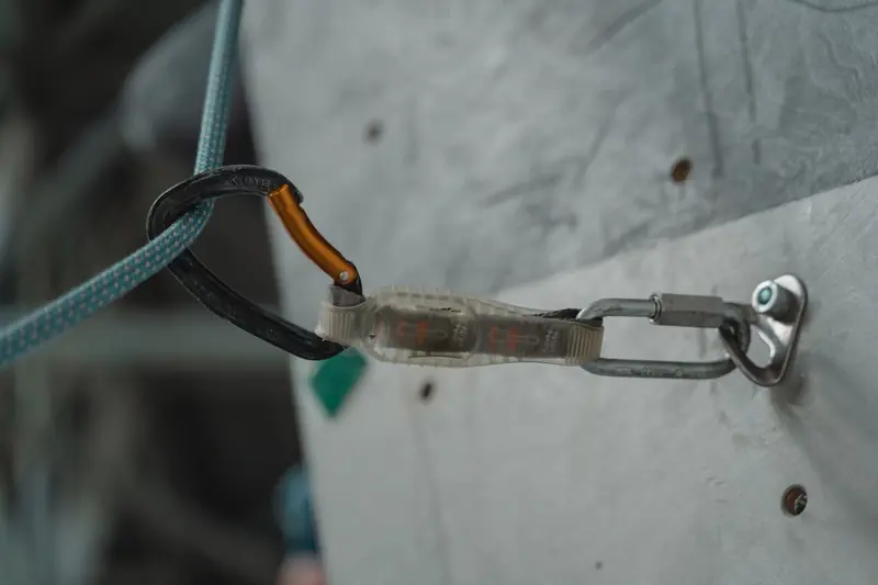 Detailed close-up of climbing gear and carabiner attached to a climbing wall, showcasing outdoor adventure equipment