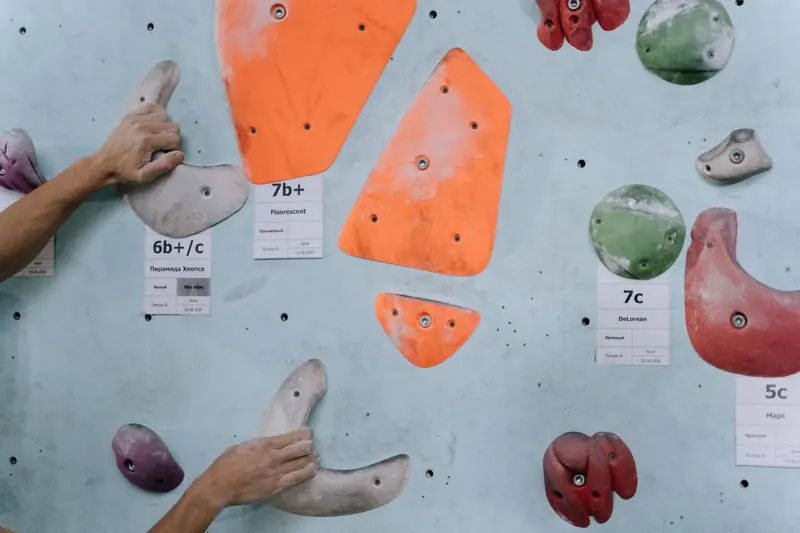 Hands gripping colorful climbing holds on an indoor climbing wall, highlighting strength and technique