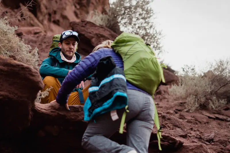 A couple enjoys rock climbing and hiking in a scenic desert landscape during daytime