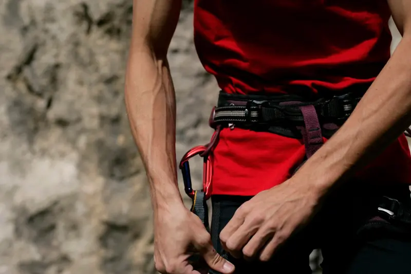 Close-up of a climber fastening a harness with climbing gear, focusing on hands