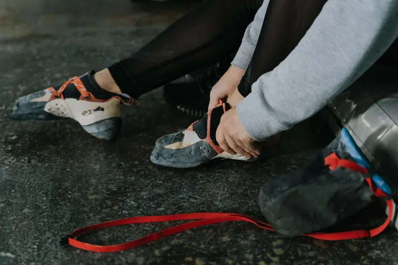 Close-up of a person putting on climbing shoes, preparing for an indoor climbing session