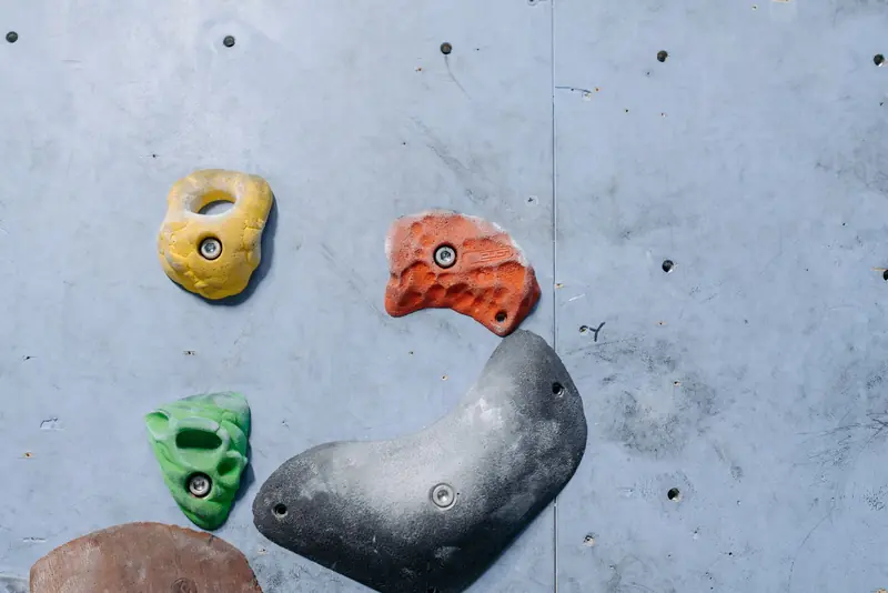 Detailed close-up of colorful climbing holds on an indoor gray rock climbing wall